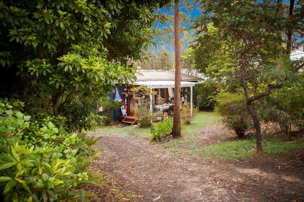 a blue house with a porch in the woods at Blue Starfish in Narrawallee