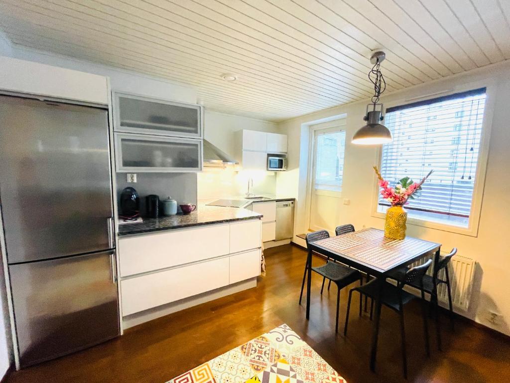 a kitchen with a table and a stainless steel refrigerator at Kaunis kattohuoneisto Lahden keskustassa in Lahti