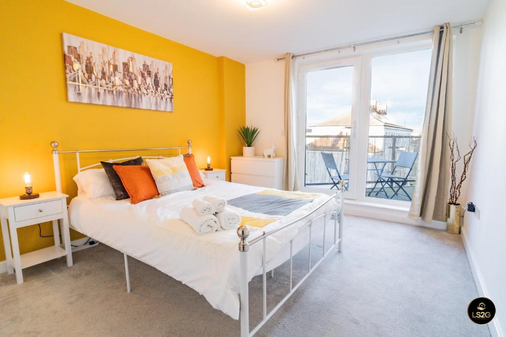 een slaapkamer met een bed met gele muren en een raam bij Spacious Apt, 2 baths, Balcony, near the O2 Arena in Londen