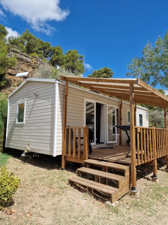 a tiny house with a porch and a deck at Mobilhome Clim Télé La Falaise 4 étoiles in Narbonne