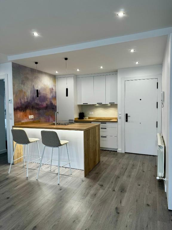 a kitchen with white cabinets and a table and chairs at Apartamentos centro I.II in El Barraco
