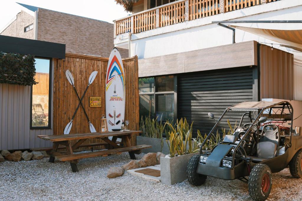 un carrito de golf estacionado junto a una casa con una tabla de surf en Búho Kite Hotel Boutique, en Salina de Rey