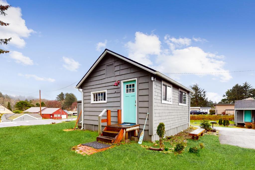 une petite maison avec une porte bleue dans une cour dans l'établissement Breakwater Inn - Shoalwater Cottage #E, à Grayland