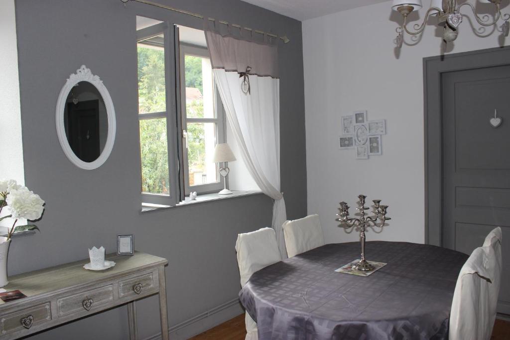 Un comedor con una mesa y un espejo. en Gite Des 3 Chateaux, en Ribeauvillé