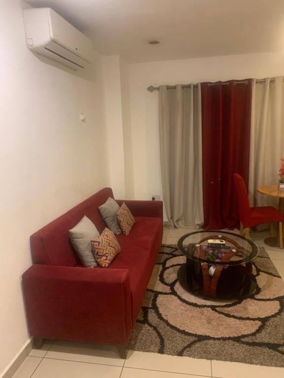 un soggiorno con divano rosso e tavolo di CityView Apartment a Accra