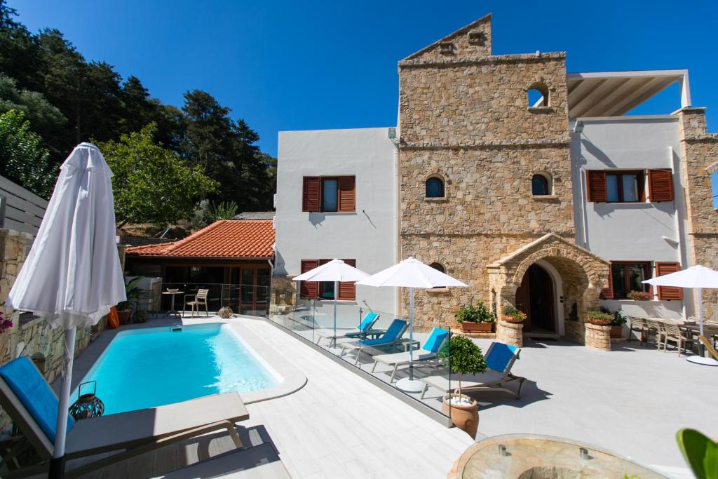 a pool with chairs and umbrellas next to a building at Grandpa's Exclusive Villa in Mixórrouma