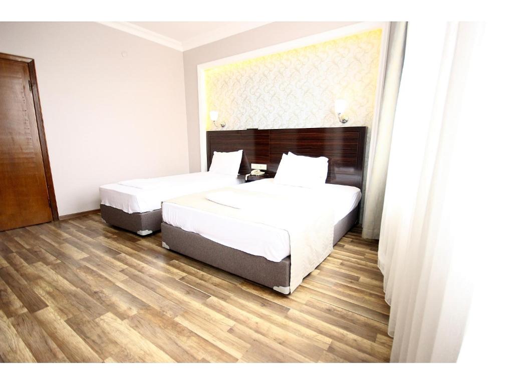 two beds in a hotel room with wood floors at Venus Hotel Taksim in Istanbul