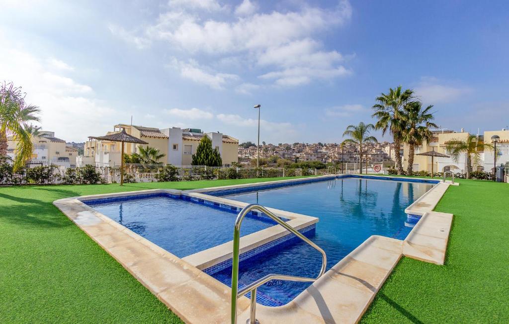 a swimming pool in the middle of a lawn with buildings at 2 Bedroom Amazing Apartment In Orihuela in Orihuela