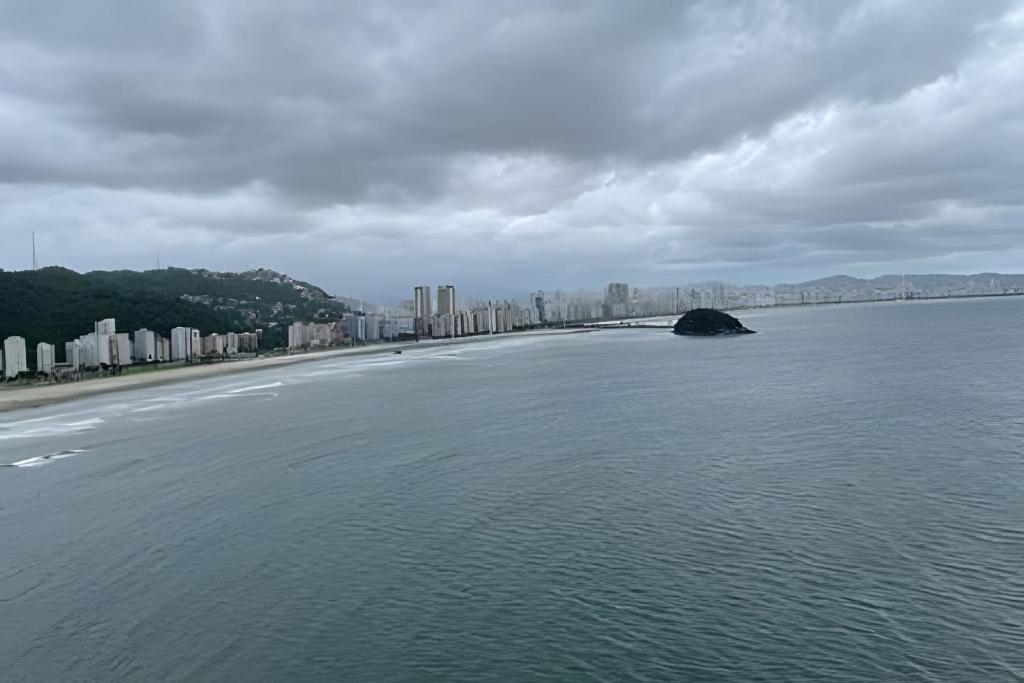 Une grande masse d'eau avec une ville en arrière-plan dans l'établissement Apartamento Paraíso da Ilha Porchat ! *Novíssimo!*, à São Vicente