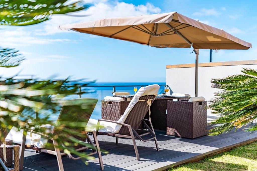 une table et des chaises sous un parasol sur une terrasse dans l'établissement Villa Alex,pool and ocean view, à Calheta