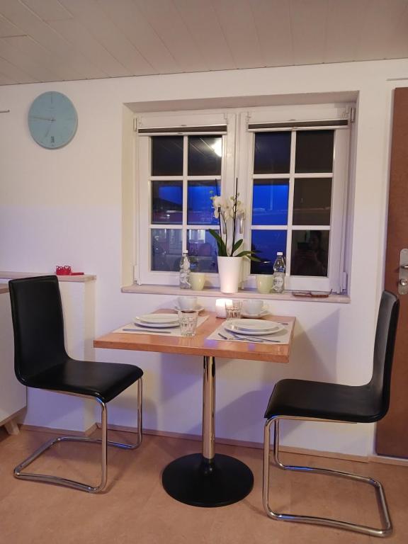 a dining room table with two black chairs and a window at Ferienwohnung in Bühler in Bühler