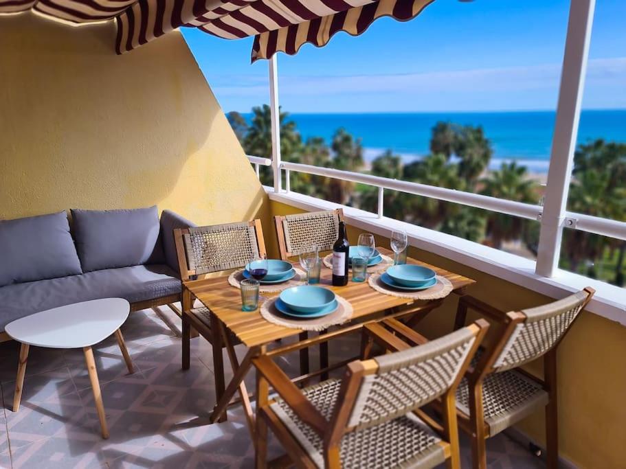 een houten tafel en stoelen op een balkon met uitzicht op de oceaan bij Los Cuentos De Natalia / The Tales Of Natalia in Oropesa del Mar