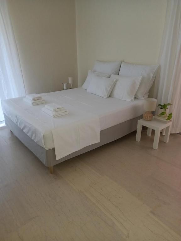 1 dormitorio con 1 cama grande con sábanas y almohadas blancas en ΝΑRIKA, en Kamena Vourla