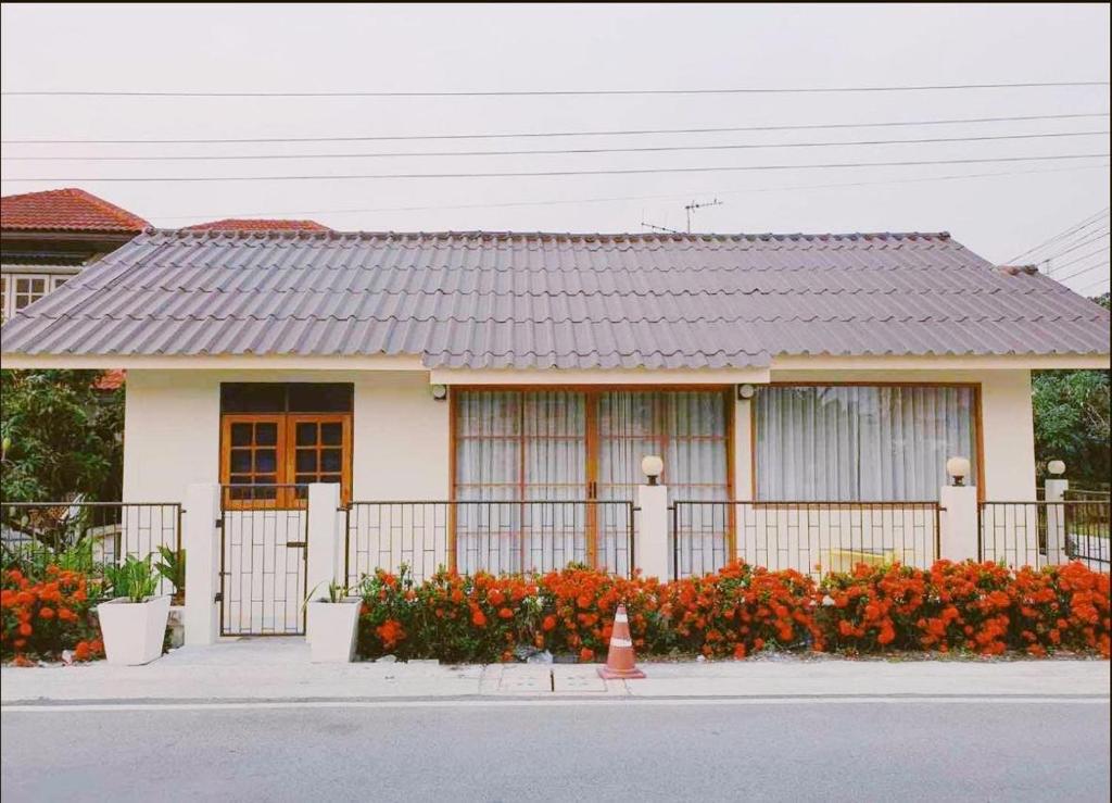 uma casa com uma cerca e flores à frente dela em Mee-Suk Home em Bang Hia