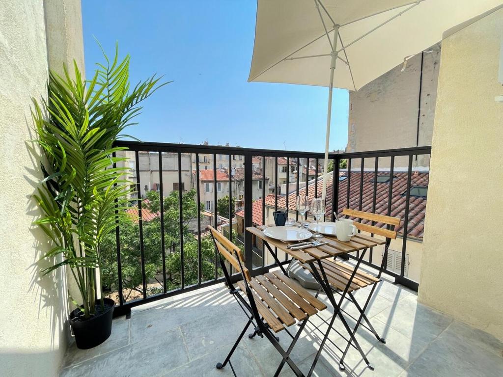 a balcony with a table and chairs and an umbrella at Little Good time in Marseille
