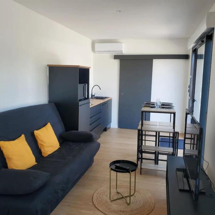 un salon avec un canapé bleu et une cuisine dans l'établissement MarcouBox, à Marcoussis