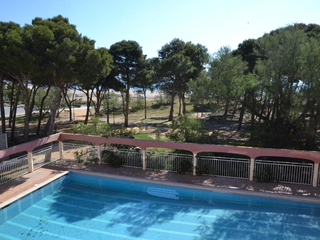une piscine avec des arbres en arrière-plan dans l'établissement Apartamento L'Estartit, 1 dormitorio, 4 personas - ES-323-60, à L'Estartit
