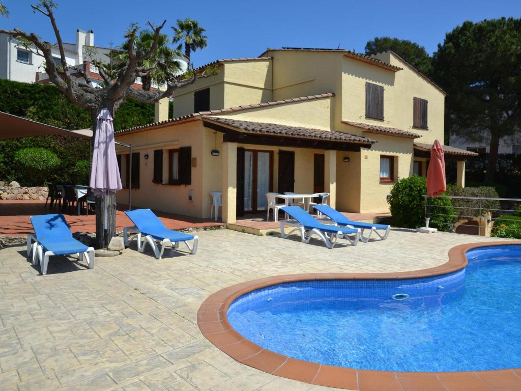 ein Pool mit Stühlen und einem Tisch und einem Haus in der Unterkunft Villa Heemstede - L'Estartit, Torre Vella - ES-323-69 in L'Estartit