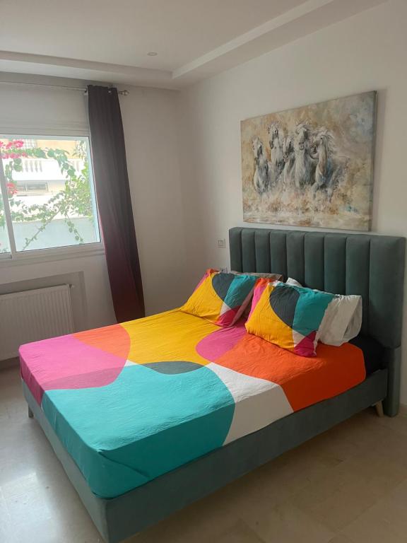 a colorful bed in a room with a window at Apart gammarth in La Marsa
