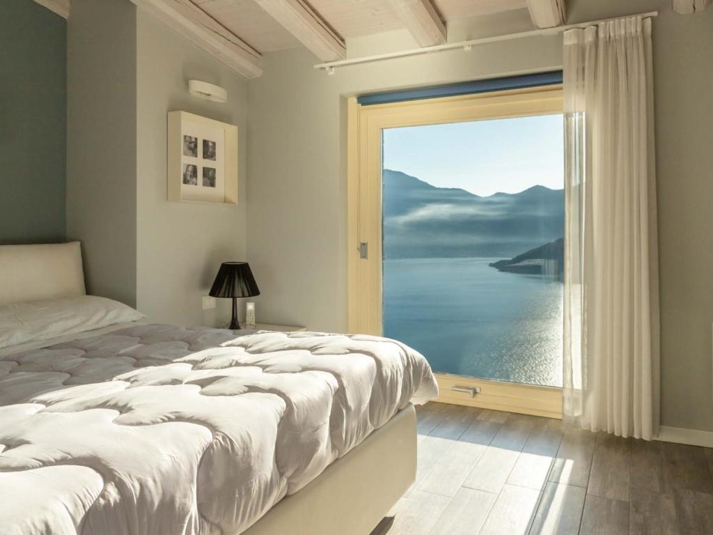 Dormitorio con ventana grande con vistas al agua en Delfi - amazing design apartment with Lake view, en Parzanica
