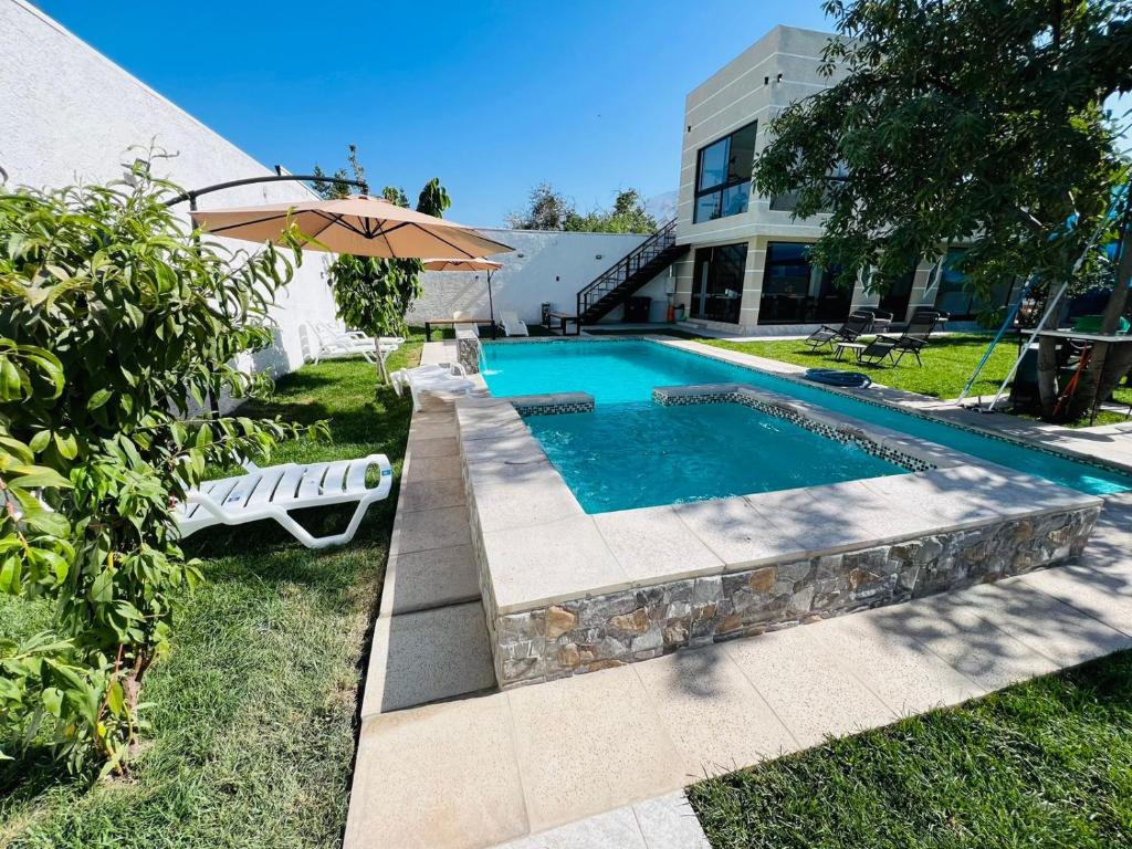 una piscina con sombrilla junto a una casa en Tu Paraíso Jim, en Santiago