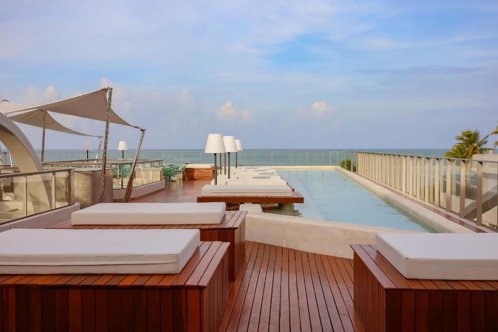 a swimming pool with chaise lounges and the ocean at Setai Yacht Premium - By Almare Flats in João Pessoa