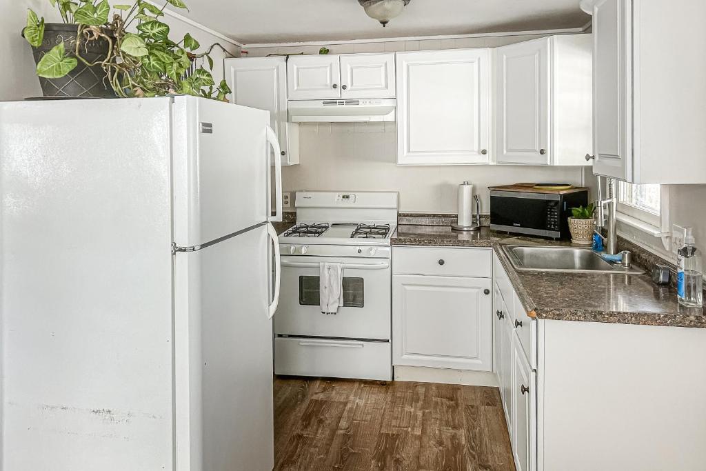 La cuisine est équipée de placards blancs et d'un réfrigérateur blanc. dans l'établissement The Cozy Cottage by the Ocean, à Hampton Beach