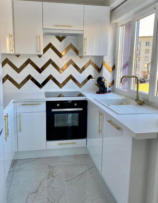 une cuisine avec des armoires blanches et un four noir dans l'établissement Appartement Cosy tout confort - Brest, à Brest