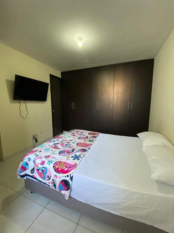 a bedroom with a white bed with a colorful blanket at Apartamento de Lujo Conjunto Marsella Real in Valledupar