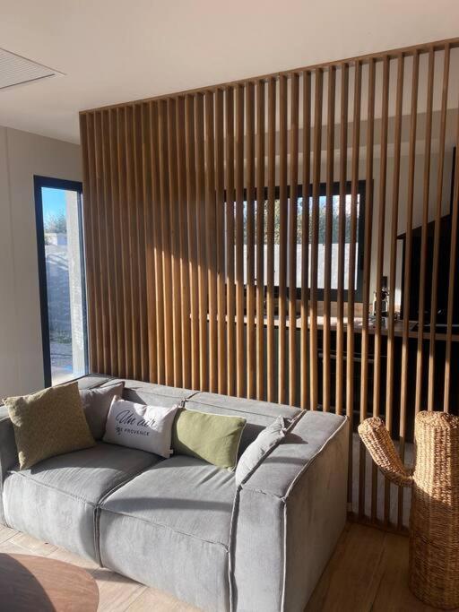 - un canapé gris dans une chambre avec une grande fenêtre dans l'établissement Gîte avec Jacuzzi Un air de Provence, à Eyguières