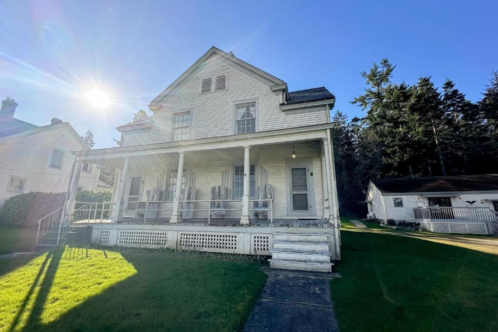 een wit huis met de zon op het gras bij Fort Casey Inn Cottage 8 in Coupeville