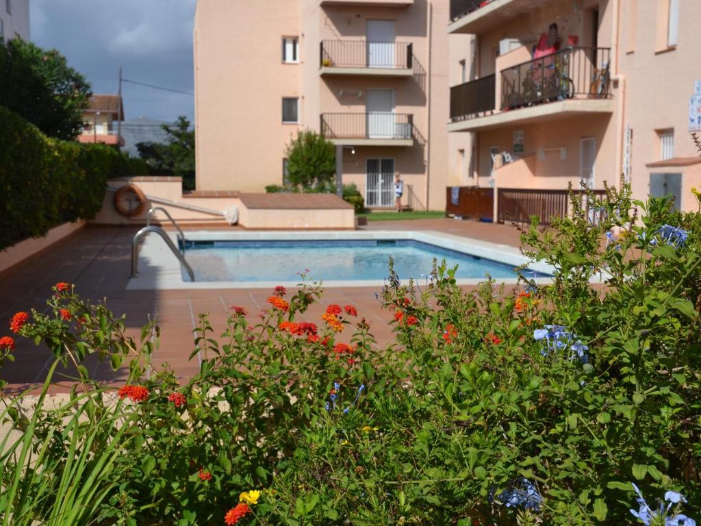 uma piscina em frente a um edifício com flores em Apartamento L'Estartit, 2 dormitorios, 4 personas - ES-323-80 em L'Estartit