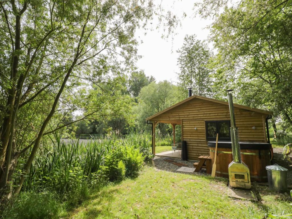 eine kleine Holzhütte auf einem Feld mit Bäumen in der Unterkunft Kingfisher in Rugby