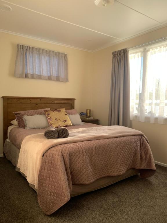 a bedroom with a large bed with a large window at The Homestead - cosy 3 bedroom house in Rotorua