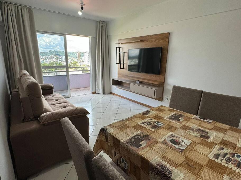 sala de estar con mesa y TV de pantalla plana en Apartamento com mobília nova 301, en Francisco Beltrão