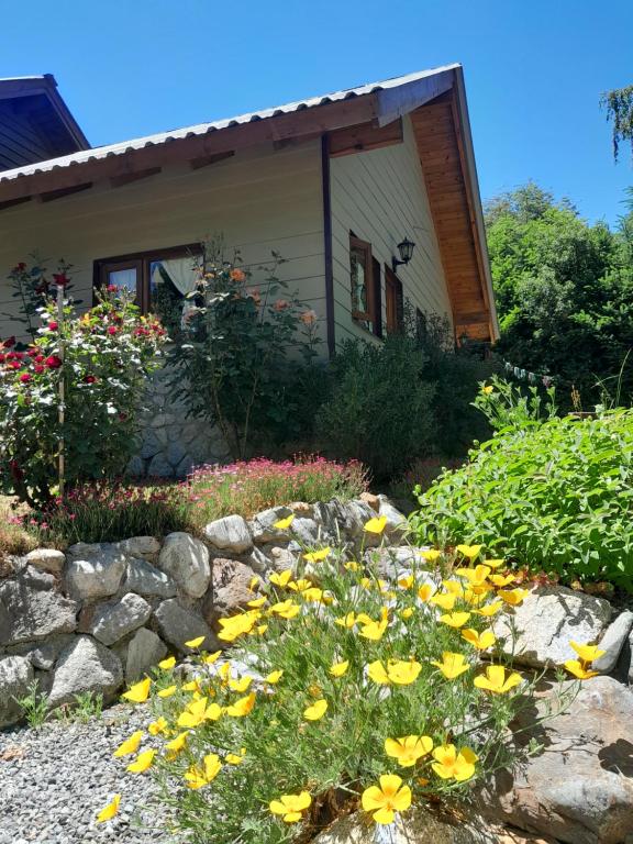 a garden with yellow flowers in front of a house at Tierras del Sur I un calido lugar in Villa La Angostura