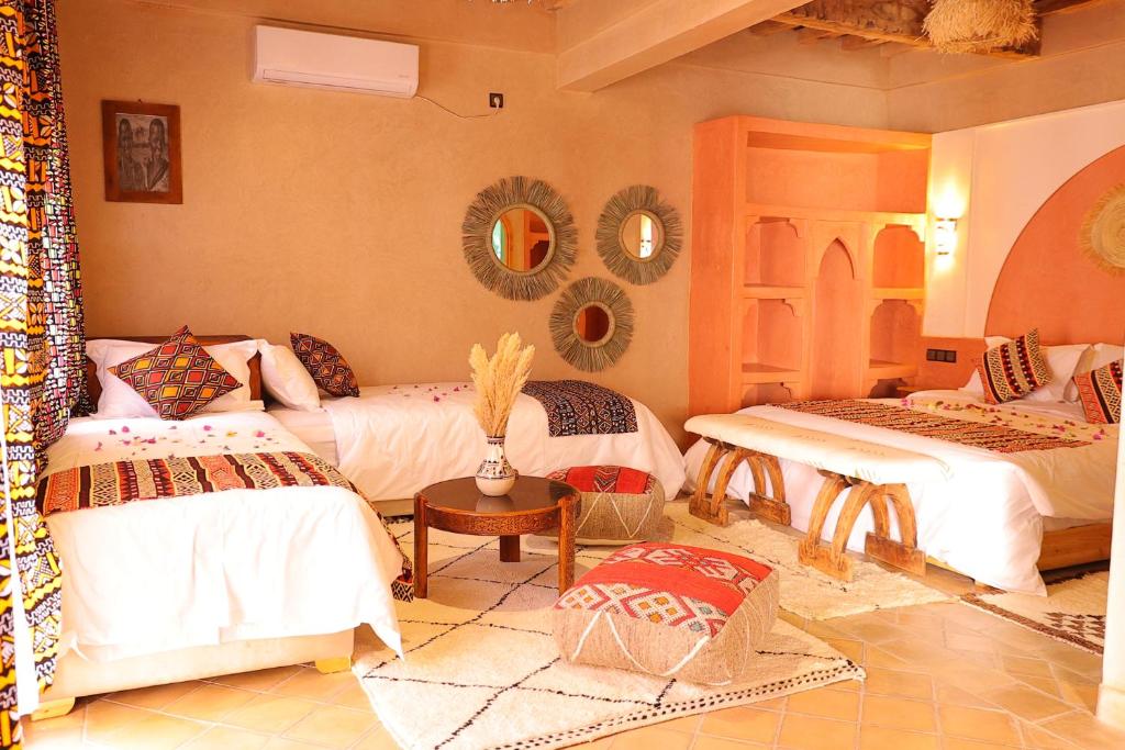 een kamer met 2 bedden, een tafel en spiegels bij riad dar susan in Zagora
