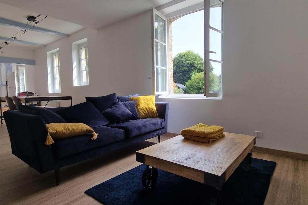 ein Wohnzimmer mit einem blauen Sofa und einem Couchtisch in der Unterkunft Le Prieuré - 4 chambres ensuite (avec salles de bain privative) in Harfleur