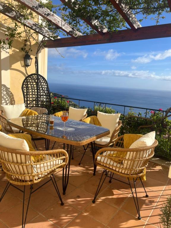 eine Terrasse mit einem Tisch, Stühlen und Meerblick in der Unterkunft Designed Villa Palheiro Village by HR Madeira in Funchal