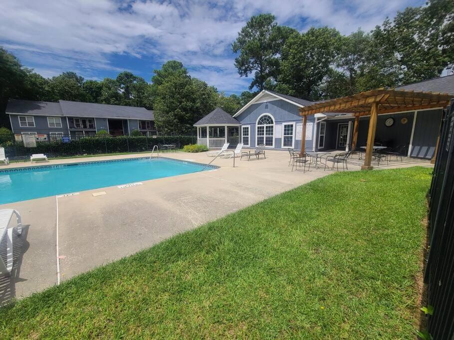 un patio trasero con piscina y una casa en A Touch of Sunshine Ideal For Long Term Stays en Fayetteville