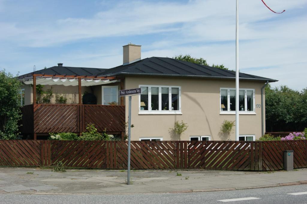 uma casa com um telhado preto e uma cerca em Skagentoppen Rooms em Skagen