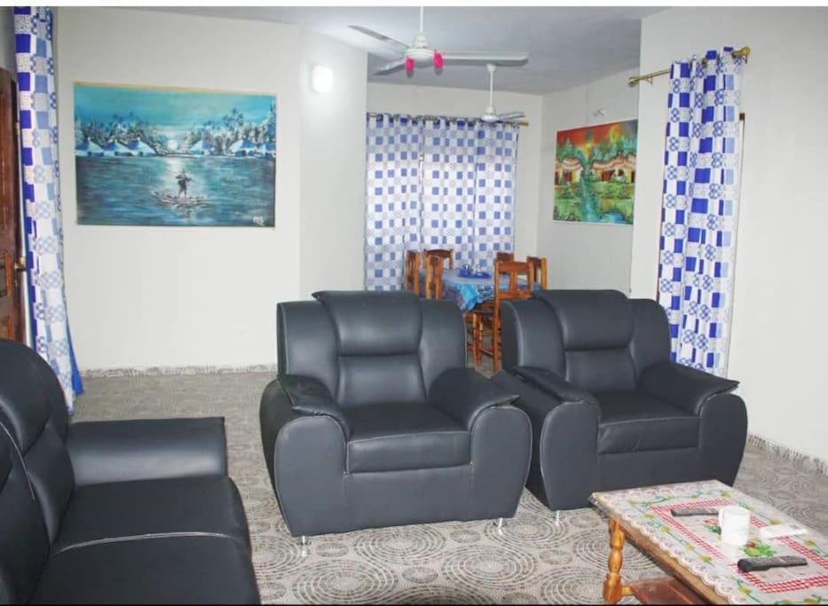 a living room with two black chairs and a table at Maison d'hôte avec paillote in Palimé