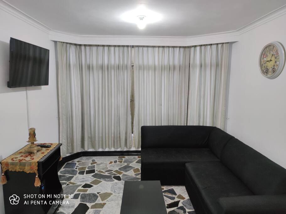 ein Wohnzimmer mit einem schwarzen Sofa und einem Tisch in der Unterkunft Alojamiento cómodo en el centro de la ciudad. in Pereira
