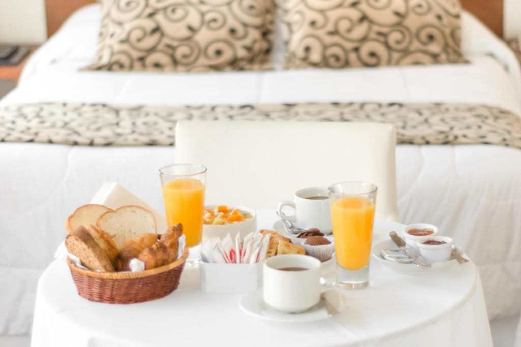 una bandeja de alimentos para el desayuno y bebidas en una cama en Palm Beach Plaza Hotel, en Montevideo