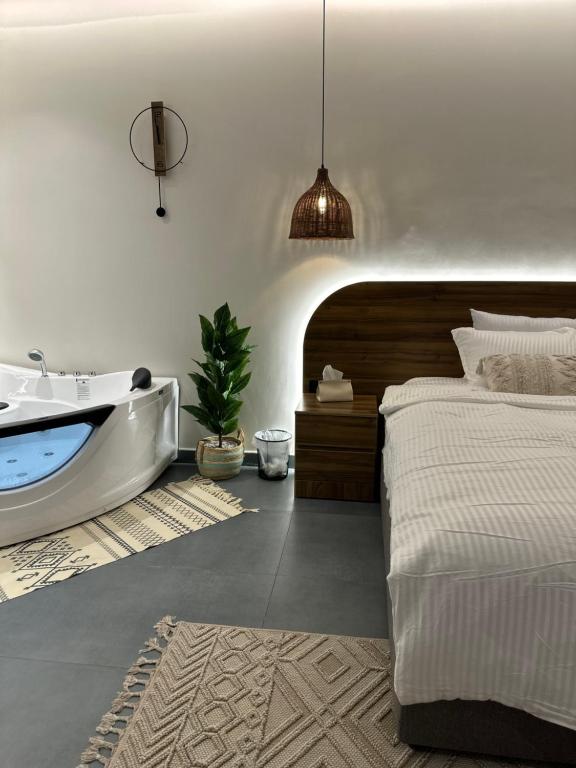 1 dormitorio con bañera, 1 cama y lavamanos en شاليه أوڤال Oval Chalet, en Al Jubail