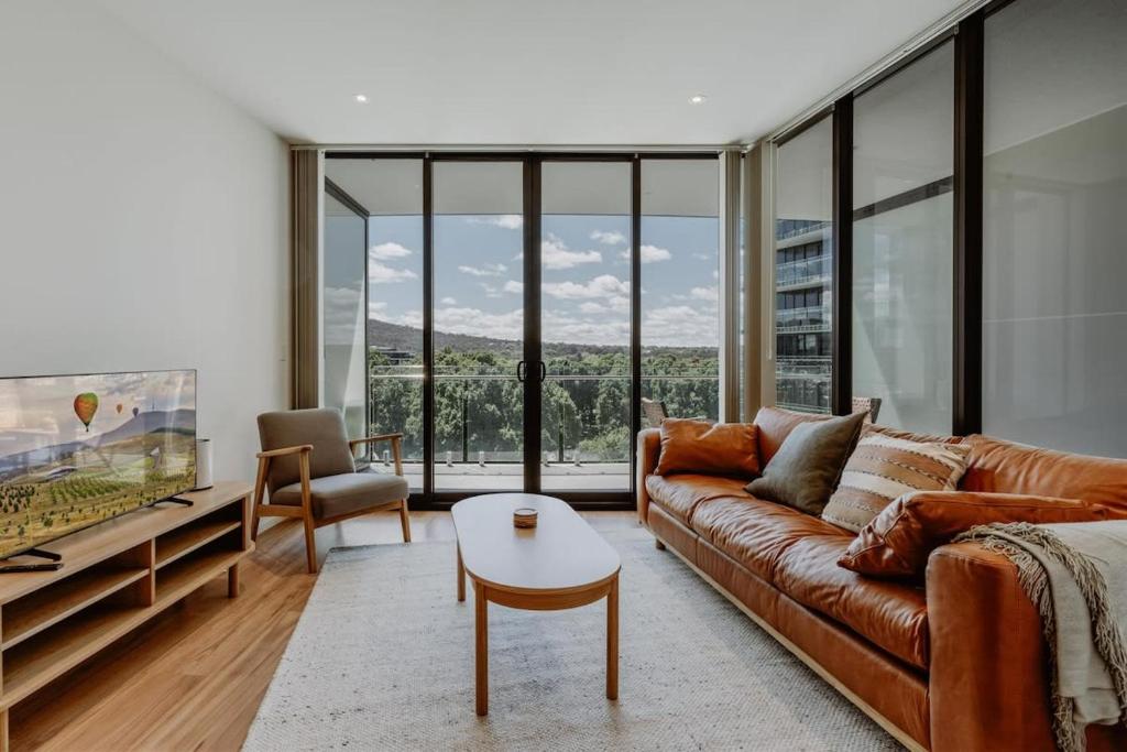 a living room with a couch and a table at Center 1-Bed with Gym, BBQ and Stunning Views in Canberra