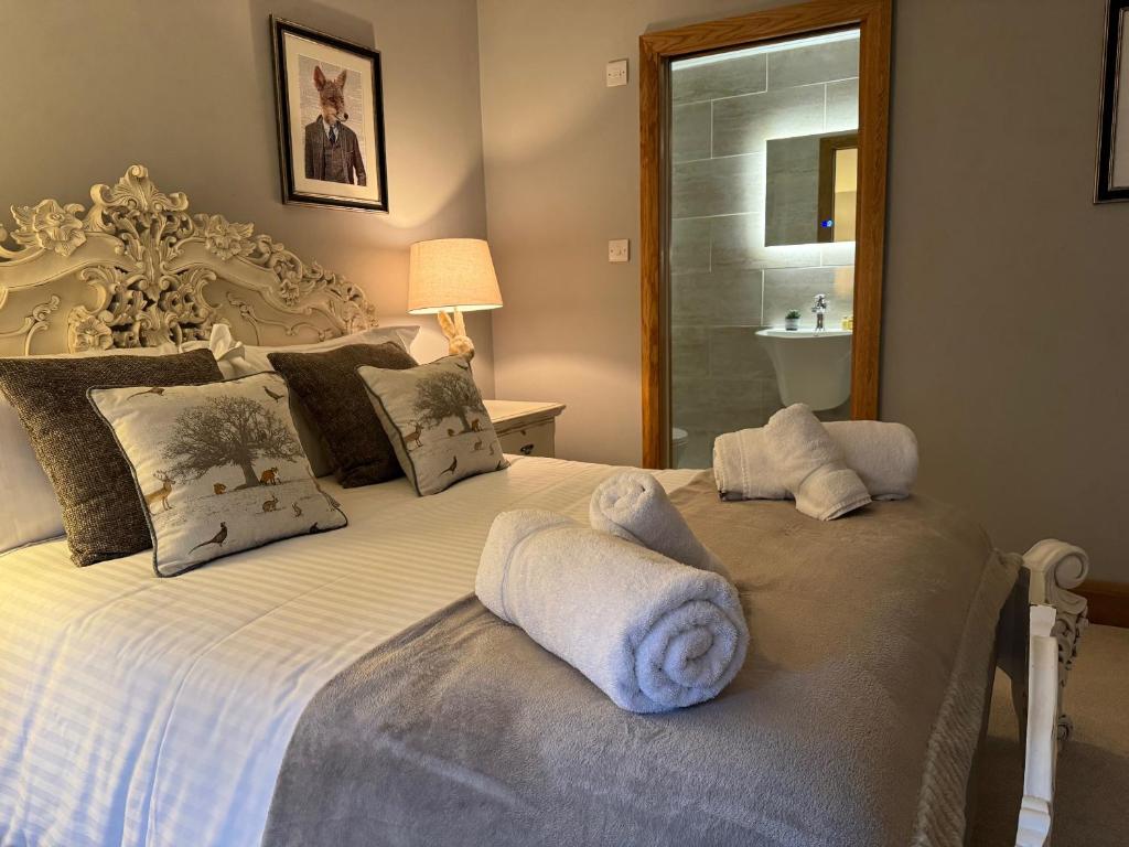 um quarto com uma cama branca e toalhas em The Coach House em Chedworth