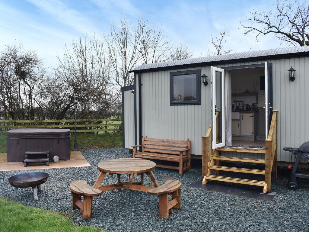 un pequeño cobertizo con una mesa de picnic y un banco en Greengill Farm Shepherds Hut- Ukc3632, en Gilcrux