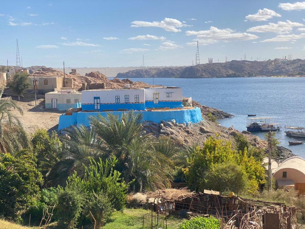 a blue building on a hill next to a body of water at Humble Nubia in Aswan