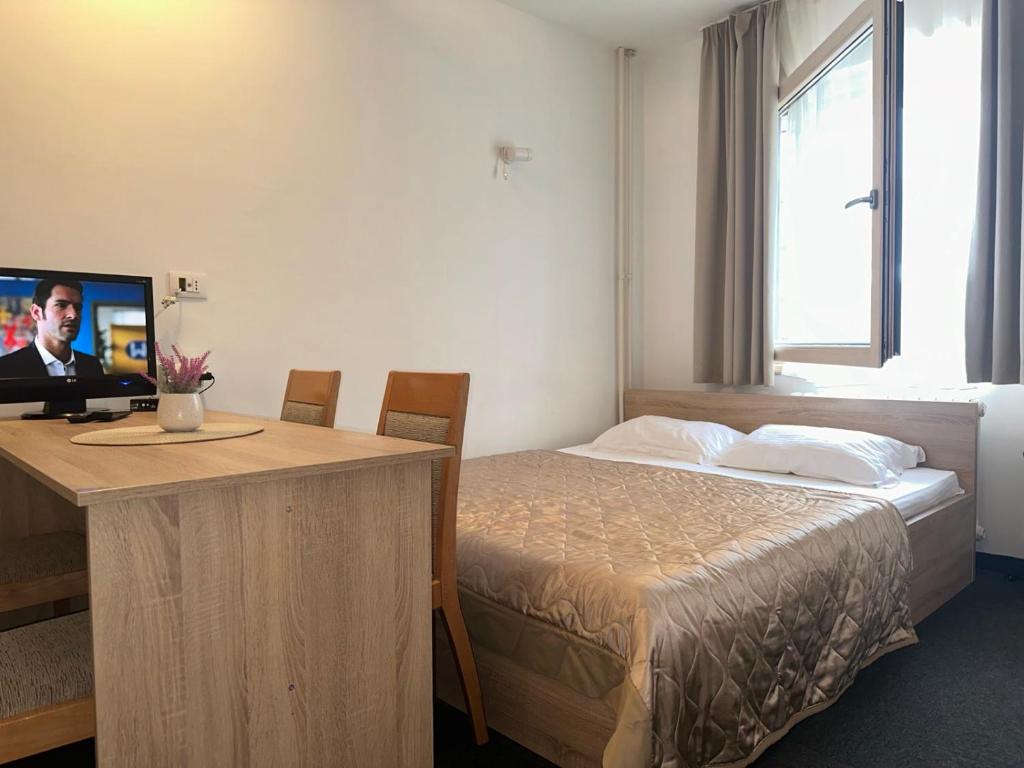 ein Hotelzimmer mit einem Bett und einem Schreibtisch mit einem TV in der Unterkunft Apartman Masa Kopaonik in Kopaonik